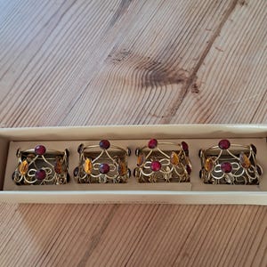 Juego vintage de 4 servilleteros The Pier UK con joyas. Caja original. Filigrana de alambre color oro estilo bohemio con piedras preciosas decorativas de ámbar y rubí.