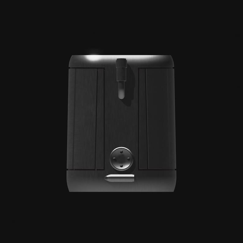 May include: A dark gray, metallic-looking box with a vertical handle and a circular button. The box has a brushed metal texture and a rectangular shape. The background is black.