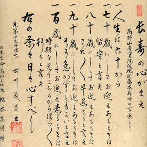 Peut inclure: Un rouleau de calligraphie à l'encre noire avec du texte japonais. Le texte dit "長寿の心がまえ" qui se traduit par "L'état d'esprit de la longévité". Le rouleau comprend également une citation d'un moine bouddhiste, "人生はおすから" qui se traduit par "La vie est un don".