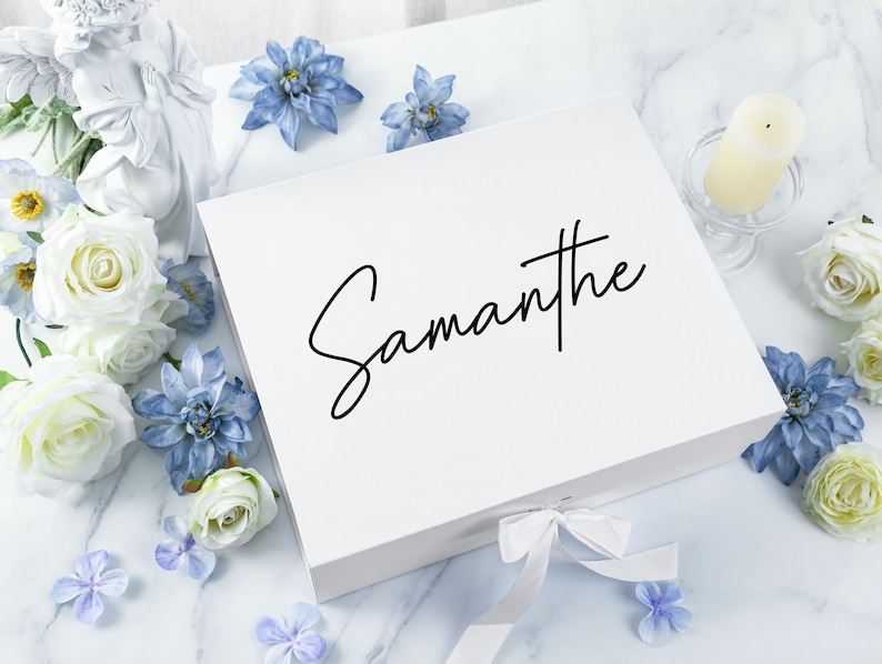 May include: White gift box with a white satin ribbon and the name "Samantha" written in black calligraphy on the top.