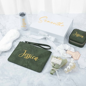 May include: A green velvet pouch with the name "Jessica" embroidered in gold lettering, a white satin sleep mask, a white box with the name "Samantha" written in gold lettering, a small green velvet jewellery box with the name "Jessica" embroidered in gold lettering, a white hair scrunchie, a small bouquet of dried flowers, a pearl hair clip, and a white tumbler with the name "Jessica" written in gold lettering.