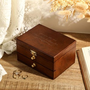 May include: A dark brown wooden jewellery box with two drawers and a hinged lid. The lid has the inscription "You are the one I have been looking for".