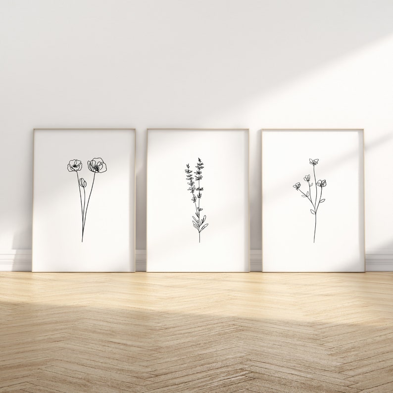 May include: Three minimalist black and white line art prints of flowers in simple frames. The prints feature a poppy, a sprig of lavender, and a cluster of small flowers.