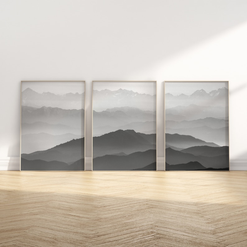 May include: Three black and white framed prints of a mountain range with fog in the background.