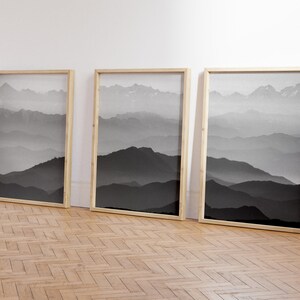 May include: Three framed black and white photographs of a mountain range with fog in the background.