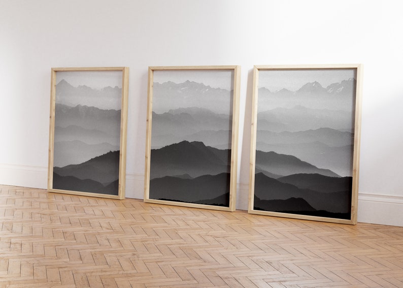 May include: Three framed black and white photographs of a mountain range with fog in the background.