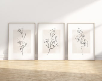 Puede incluir: Tres impresiones enmarcadas con dibujos de línea negra de flores de magnolia sobre un fondo beige.