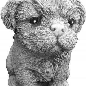May include: A small, gray, concrete statue of a dog with a fluffy, furry texture. The dog is sitting with its head tilted down and its eyes closed.