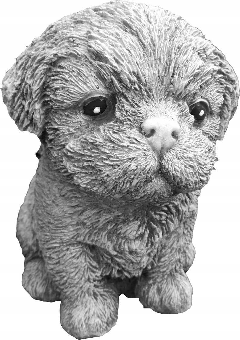 May include: A small, gray, concrete statue of a dog with a fluffy, furry texture. The dog is sitting with its head tilted down and its eyes closed.