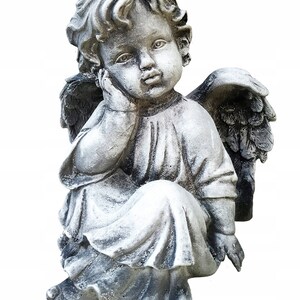 May include: A gray stone cherub statue with wings, sitting with its head resting on its hand. The cherub is wearing a long robe and has a thoughtful expression.