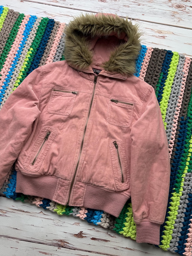 May include: A pink corduroy jacket with a faux fur lined hood. The jacket has a zipper closure and multiple pockets.