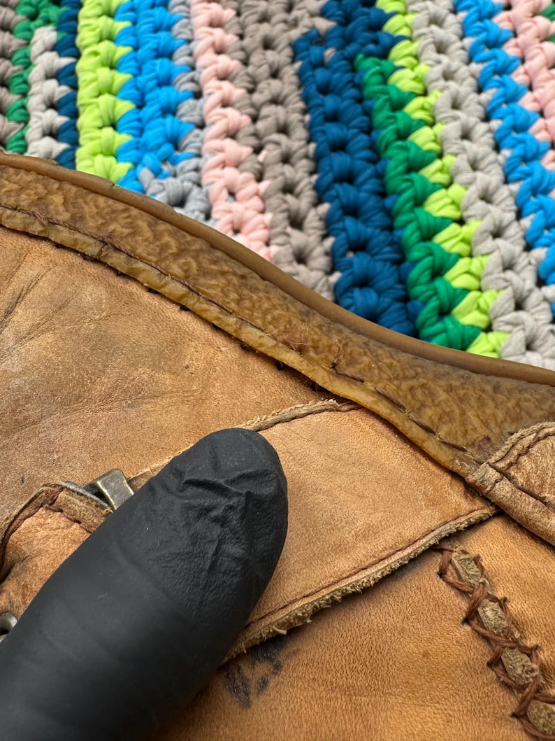 May include: Close-up of a brown leather boot with a seam along the top edge. The boot is worn and has a dark brown leather sole.