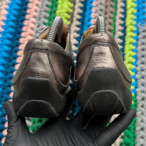 May include: A pair of black leather shoes with a rounded toe and a textured sole. The shoes are worn and have a slight sheen.