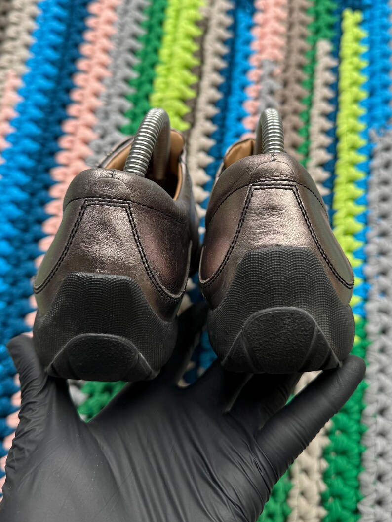 May include: A pair of black leather shoes with a rounded toe and a textured sole. The shoes are worn and have a slight sheen.