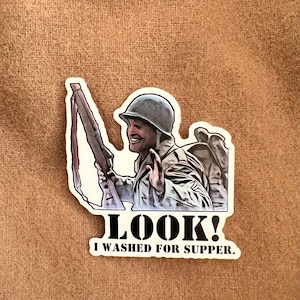 May include: A sticker featuring a cartoon soldier holding a rifle and saying "LOOK! I WASHED FOR SUPPER."