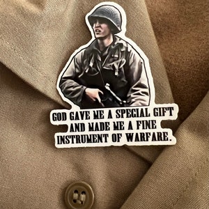 May include: A sticker featuring a black and white image of a soldier holding a rifle. The sticker has the text "GOD GAVE ME A SPECIAL GIFT AND MADE ME A FINE INSTRUMENT OF WARFARE."