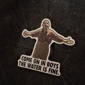 May include: A sticker featuring a man with his arms outstretched, with the text "Come on in boys the water is fine."