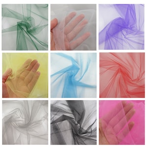 May include: Assortment of tulle fabric in various colours, including green, white, purple, yellow, blue, red, grey, black, and pink. The fabric is sheer and delicate, with a soft, flowing texture.