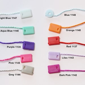 May include: Assortment of colourful plastic tags with string attached. The tags are in various colours, including light blue, aqua blue, purple, pink, grey, dark pink, orange, red, lilac, and blue. Each tag has a corresponding number printed on it.