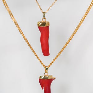 May include: Two gold chains with red coral pendants. The coral is a natural, organic shape.