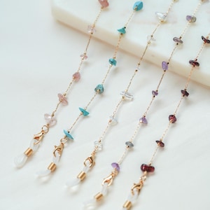 May include: Five gold chains with different colored gemstone beads and gold clasps. The chains are for holding glasses or sunglasses.