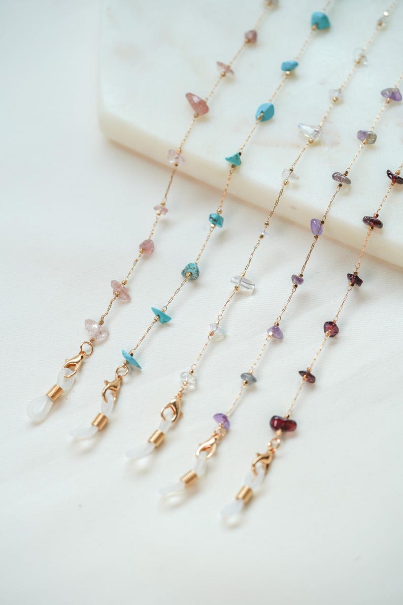 May include: Five gold chains with different colored gemstone beads and gold clasps. The chains are for holding glasses or sunglasses.