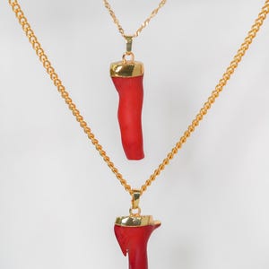 May include: Two gold chains with red coral pendants. The coral is a natural material and has a unique shape.