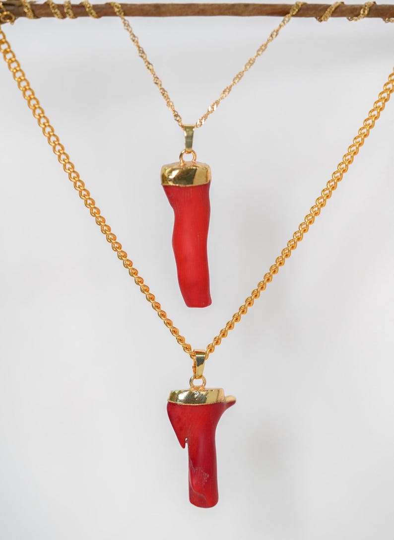 May include: Two gold chains with red coral pendants. The coral is a natural material and has a unique shape.