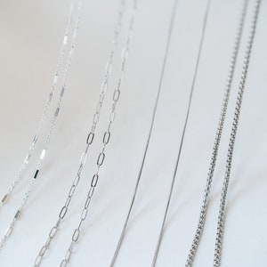 May include: A collection of six silver chains of different styles and thicknesses, displayed against a white background.