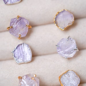 May include: A set of six amethyst crystal earrings in a jewelry box. The earrings are made with raw amethyst crystals and gold or silver settings.