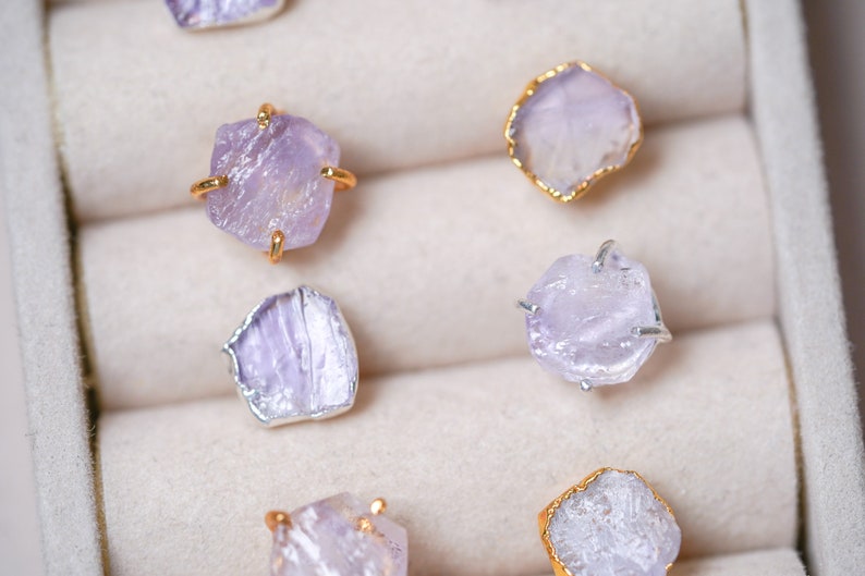 May include: A set of six amethyst crystal earrings in a jewelry box. The earrings are made with raw amethyst crystals and gold or silver settings.