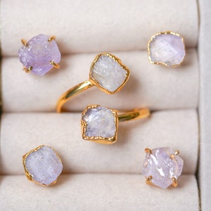 May include: Five rings with purple and white gemstone settings in a white velvet ring box.