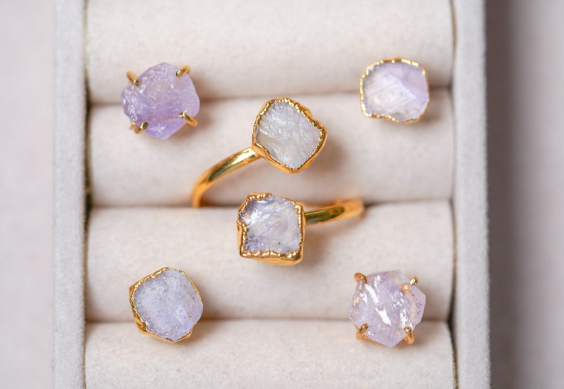 May include: Five rings with purple and white gemstone settings in a white velvet ring box.