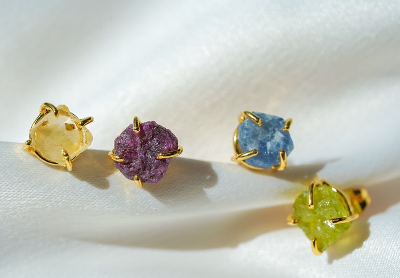 Stud gemstone earrings. Style A has a more smooth stone that is enclosed on the sides with gold-plated brass. Style B has four gold-plated brass extensions keeping the more textured stone secure. Both styles have push-back closures.