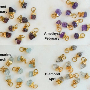 May include: Assortment of raw gemstone charms with gold-plated jump rings. Garnet, Amethyst, Aquamarine, and Diamond charms are shown in separate groups. Each group is labeled with the gemstone name and corresponding birth month.