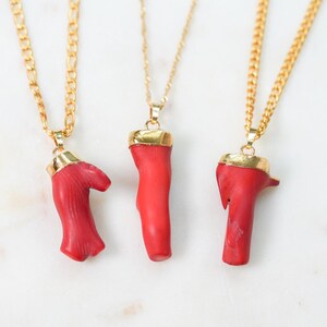 May include: Three gold chain necklaces with red coral pendants. The coral is a natural material and each pendant is unique in shape and size.