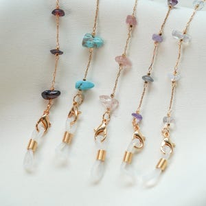 May include: Five gold chains with different colored gemstone beads and clear plastic ends. The chains are for holding glasses or face masks.