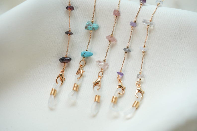 May include: Five gold chains with different colored gemstone beads and clear plastic ends. The chains are for holding glasses or face masks.