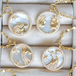 May include: Four gold necklaces with white mother-of-pearl pendants featuring zodiac signs. Each pendant is surrounded by a circle of clear cubic zirconia stones.