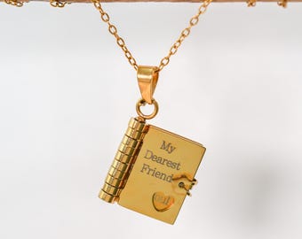 May include: A gold-colored pendant necklace featuring a miniature book charm. The book charm is engraved with the words "My Dearest Friend" and a heart symbol. The necklace hangs from a delicate gold chain.