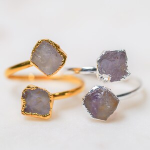 May include: Three rings with amethyst stones. Two rings are gold and one is silver.