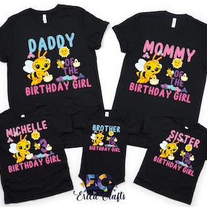 Pu&ograve; includere: T-shirt neri con grafica colorata per una festa di compleanno. Le magliette presentano un'ape dei cartoni animati con la scritta "Daddy", "Mommy", "Michelle", "Brother" e "Sister" con "Birthday Girl".