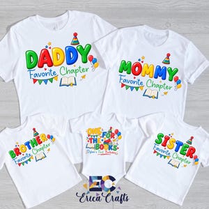 May include: A set of five white t-shirts and one white baby bodysuit featuring colorful graphic prints. The shirts display the text Daddy, Mommy, Brother, or Sister followed by Favorite Chapter, while the bodysuit says One for the Books.