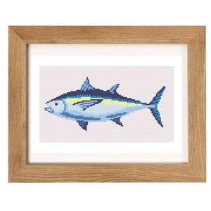 May include: A framed cross-stitch embroidery of a blue and yellow tuna fish. The fish is swimming to the right and has a detailed design.