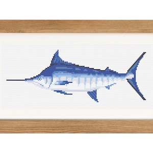 以下が含まれることがあります： 白い背景に青いマルリンの魚が刺繍された、額装されたクロスステッチ刺繍です。