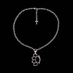 Op de afbeelding: Een zilveren ketting met een zilveren kruis hanger en een zilveren knokkelstoot hanger.