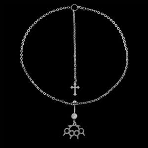 Op de afbeelding: Zilverkleurige lichaamsketting met een kruisbedel en een boksbeugelbedel. De ketting heeft een cirkelvormig ontwerp met een hangend kruis en een navelring met een boksbeugelbedel.
