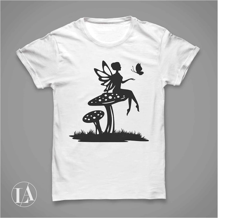 Puede incluir: Camiseta blanca con una silueta negra de un hada sentada en un hongo con una mariposa volando cerca.