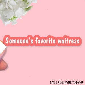 May include: A pink sticker with the text "Someone's favorite waitress" in white, outlined in a coral color. The sticker is on a pink background, with white flowers in the upper left corner.