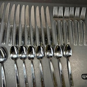 以下が含まれることがあります： 暗い表面にきちんと配置された、ナイフ、フォーク、スプーンを含むステンレス鋼のカトラリーセット。カトラリーはシンプルでエレガントなデザインで、光を反射します。毎日の食事や特別な機会に最適です。